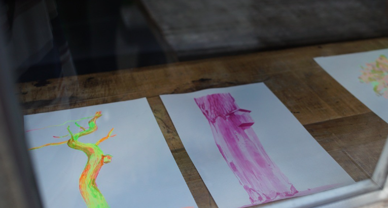 Kleurrijke tekeningen van bomen tentoongesteld op een houten tafel
